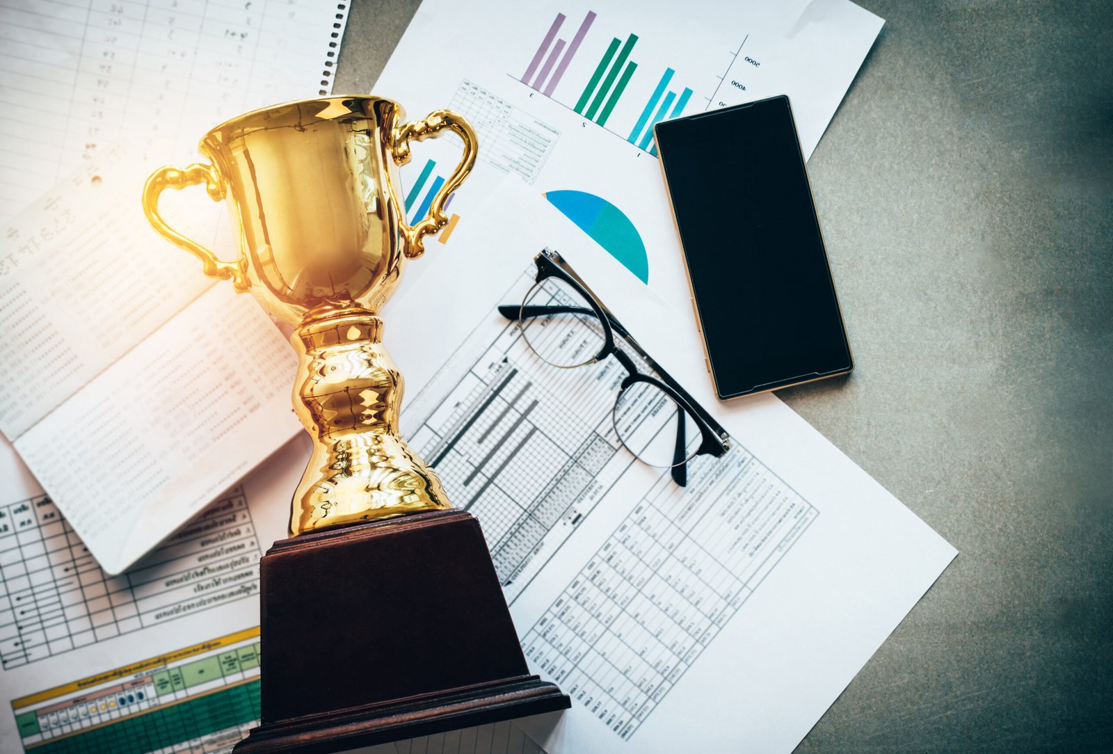 Success concept,a gold trophy with business Information at the desk in office.